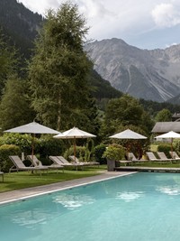 Wohlfühlen im Hotel Valavier Ein großzügiger Außenpool des Hotel Valavier lädt zum Entspannen ein. Umgeben von grünen Wiesen, Liegestühlen und Sonnenschirmen eröffnet sich ein beeindruckender Blick auf die Bergwelt des Brandnertals.