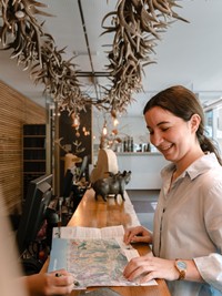 Ausbildung mit Herz im Valavier Eine Mitarbeiterin lernt gemeinsam mit einem Kollegen an der Rezeption des Hotel Valavier. Zusammen betrachten sie eine Wanderkarte und tauschen sich dabei über die Region aus.
