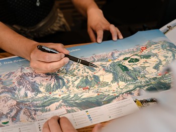 Lernen mit Blick auf die Region Zwei Personen betrachten gemeinsam eine Wanderkarte des Brandnertals und tauschen sich über die Region aus. Dabei lernen sie die Wanderwege und Ausflugsziele in der Umgebung kennen.