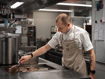 Mit Leidenschaft in der Küche Ein Mitarbeiter des Hotel Valavier bereitet in der Küche Fleisch für die nächste Mahlzeit vor. Mit Konzentration und Leidenschaft arbeitet er an der Zubereitung der Speisen.