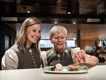 Lernen im Team Eine Mitarbeiterin zeigt einer jüngeren Kollegin, wie ein Dessert im Hotel Valavier angerichtet wird.