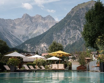 Ein Arbeitsplatz mit Bergpanorama Ruhiger Poolbereich mit Sonnenschirmen und Liegen vor dem Bergpanorama des Brandnertals.