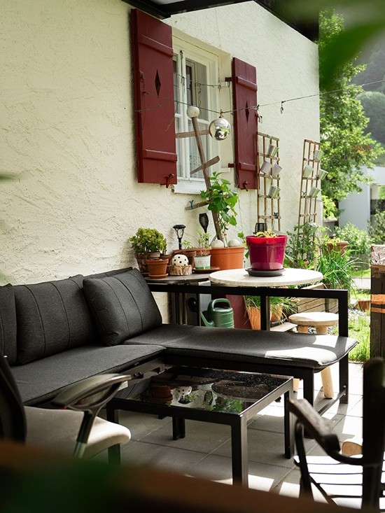 Der Außenbereich des Mitarbeiterhauses bietet eine gemütliche Sitzecke mit viel Grün und liebevollen Details. Hier können Mitarbeiter entspannen und die ruhige Atmosphäre genießen.